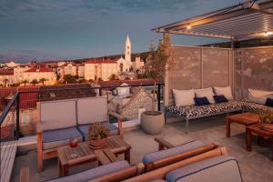 a balcony with chairs and tables and a view of a city at Hotel Osam - Adults Only in Supetar