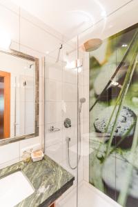 a bathroom with a shower with a sink and a mirror at Matreier Tauernhaus in Matrei in Osttirol