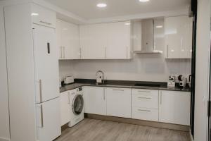 a kitchen with white cabinets and a washer and dryer at Charming loft next to wonders of Cordoba in Córdoba