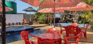 a patio with red tables and chairs and a pool at MOZBEVOK Coconut View Resort in Ponta do Ouro