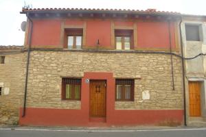 a stone building with orange doors on a street at Casa rural, 15 personas, 7 habitaciones,gran salón in Lazagurría