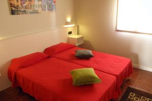 a bedroom with a red bed with two pillows on it at Casa rural, 15 personas, 7 habitaciones,gran salón in Lazagurría
