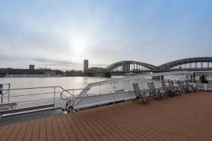 a boat on the water with a bridge in the background at Hotelship KD Moment Köln in Cologne