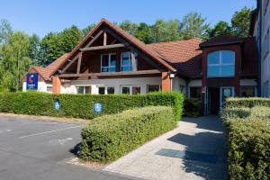 a house with bushes in front of a street at Comfort Hotel Lille Lomme in Lomme