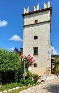 un edificio con una torre con fiori rosa di fronte di Azienda Agrituristica Corteforte a Fumane