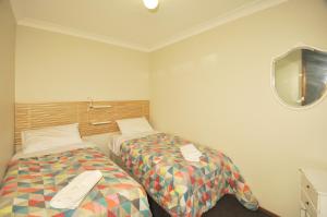 a room with two beds and a tv on the wall at Katoomba Townhouses in Katoomba