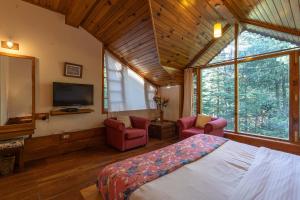 a bedroom with a bed and two chairs and a tv at StayVista at Casa Bella Vista- Luxury 6 BR close to Mall Road with Bonfire and View in Manāli