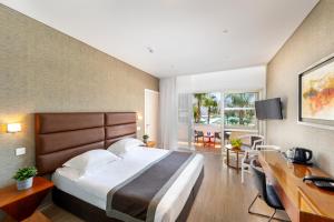 a hotel room with a large bed and a desk and a desk at Faros Hotel Ayia Napa in Ayia Napa