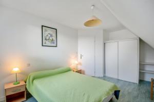 1 dormitorio con 1 cama verde y 2 lámparas en Appartement confortable avec terrasse à Arzon - 60 m², en Arzon