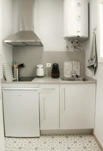 a kitchen with white cabinets and a sink at Apartamentos en la Plaza Doña Elvira, 7 in Seville