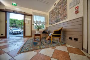 un corridoio con 2 sedie e un tavolo su un pavimento piastrellato di Hotel Giotto a Padova