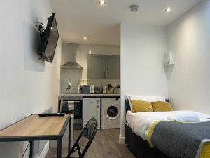 a bedroom with a bed and a table and a kitchen at Queen Street Apartments in Wolverhampton