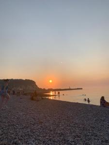 un grupo de personas en una playa al atardecer en Spacieux T3 coeur de ville en Saint-Valery-en-Caux