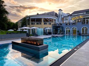 a large building with a swimming pool with a fire fountain at Steigenberger Hotel Der Sonnenhof in Bad Wörishofen