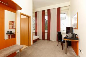 Habitación con escritorio, ordenador y dormitorio. en Hotel am Rhein, en Wesseling