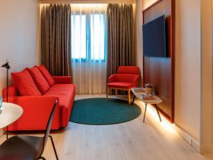 a living room with a red couch and a table at Novotel Madrid City Las Ventas in Madrid