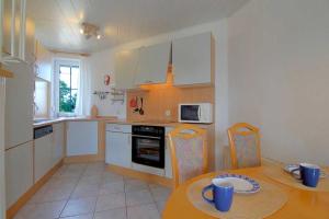 a kitchen with a table and a kitchen with white cabinets at STW24a Bungalow in Dorum Neufeld