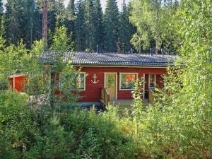 a red cabin in the middle of a forest at Villa Anchor in Kouvola
