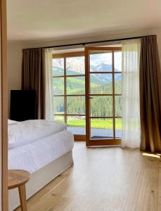 a bedroom with a bed and a large window at Cosy Winter - Luxury Chalet at the foot of the Dolomites in La Villa