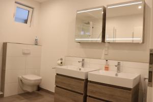 a bathroom with two sinks and a toilet and a mirror at Apartment "Anne" in ehemaliger Schuhfabrik in Herxheim