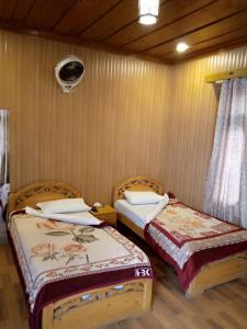 twee bedden in een kamer met houten wanden bij Forest Valley Cottages in Kārandūkai