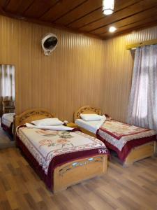 twee bedden in een kamer met houten vloeren bij Forest Valley Cottages in Kārandūkai