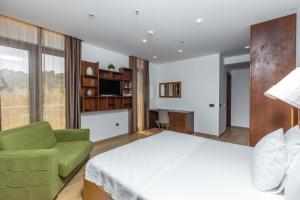 a bedroom with a large bed and a green couch at Hotel Plaza Lucice in Petrovac na Moru