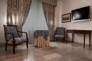 two chairs and a table in a room with a television at Hotel Juanito in Baeza