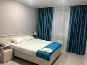 1 dormitorio con 1 cama con cortinas azules en HANYM HOTEL, en Atyraū