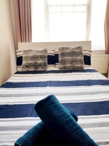 a bed with blue and white pillows and a window at Waterloo Rooms in London
