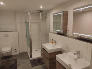 a bathroom with two sinks and a shower and a toilet at Apartment "Marie" in ehemaliger Schuhfabrik in Herxheim