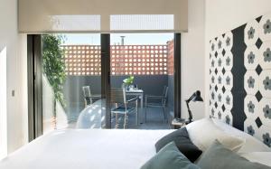 a bedroom with a bed and a balcony with a table at Eric Vökel Boutique Apartments - BCN Suites in Barcelona