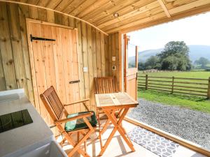 two chairs and a table on the porch of a cabin at Claerwen in Llandrindod Wells