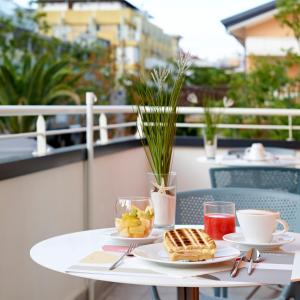 een tafel met twee borden eten en drinken op een balkon bij Art Hotel Principe in Lignano Sabbiadoro