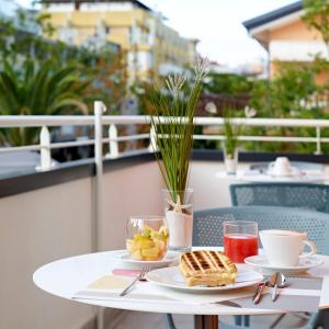 - une table avec deux assiettes de nourriture et de boissons sur un balcon dans l'établissement Art Hotel Principe, à Lignano Sabbiadoro