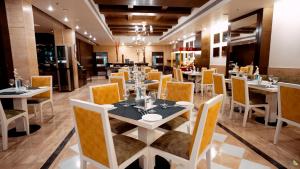 a dining room with white tables and yellow chairs at Leisure Inn Grand Chanakya in Jaipur