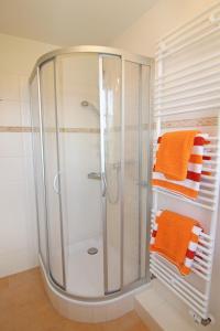 ein Badezimmer mit einer Dusche und zwei orangefarbenen Handtüchern in der Unterkunft Sünje in Westerland