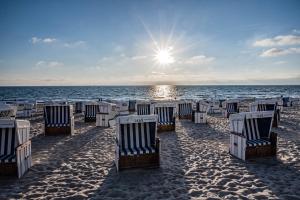 uma fila de cadeiras de praia numa praia arenosa em Westen em Westerland