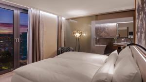 - une chambre avec un grand lit blanc et une fenêtre dans l'établissement Hotel Stadt Lörrach, à Lörrach