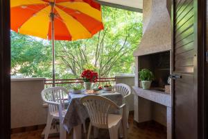 - une table et des chaises avec un parasol sur la terrasse couverte dans l'établissement Delle Rose, à Cavallino-Treporti