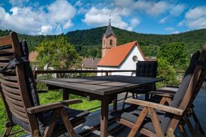 a wooden table and chairs on a deck with a church at Haus-amBrunnen in Nothweiler