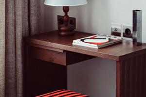 a wooden table with a lamp and a book on it at Hotel des Académies et des Arts in Paris