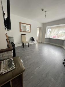 een lege woonkamer met houten vloeren en een spiegel bij Cranmore Guest House in Solihull