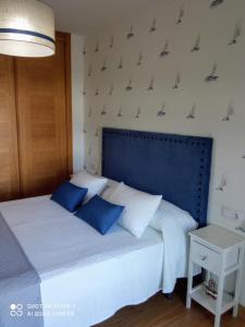 um quarto com uma cama com duas almofadas azuis em El pisito de Lourizan em Pontevedra
