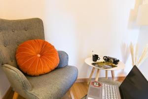a pumpkin pillow sitting on a chair with a laptop at Élégant - Le RemarKable - Parking in Saverne