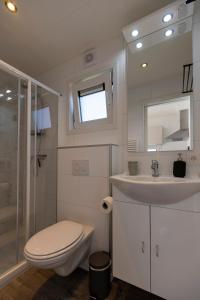 a white bathroom with a toilet and a sink at At Sea Zoutelande - Nieuwstraat 15a in Zoutelande