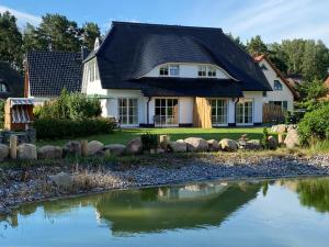 a house with a pond in front of it at Ferien-im-Duenenhaus-Ole in Glowe