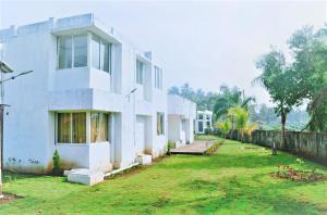 a white house with a yard in front of it at Alibaug Castle in Alibaug