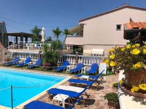 una piscina con tumbonas azules junto a un edificio en Villa Mary 1 & fresh!, en Skala Sotiros