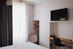 a bedroom with a bed and a tv and a chair at Hôtel-Restaurant Villa Métis in Les Herbiers